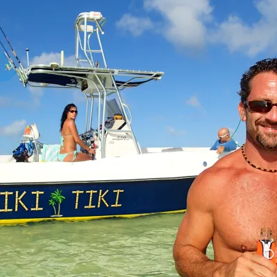 Man standing in water with boat behind him