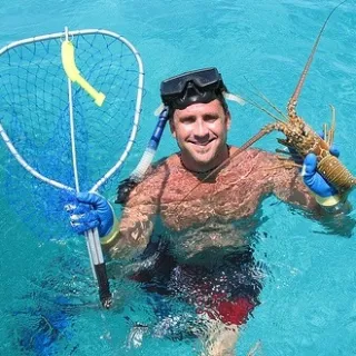 Man in the water holding a lobster he caught