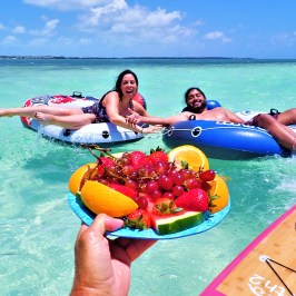 People sitting on inner tubes in clear shallow water