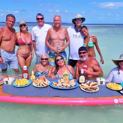 Group of people in the water with paddleboard of food in front of them
