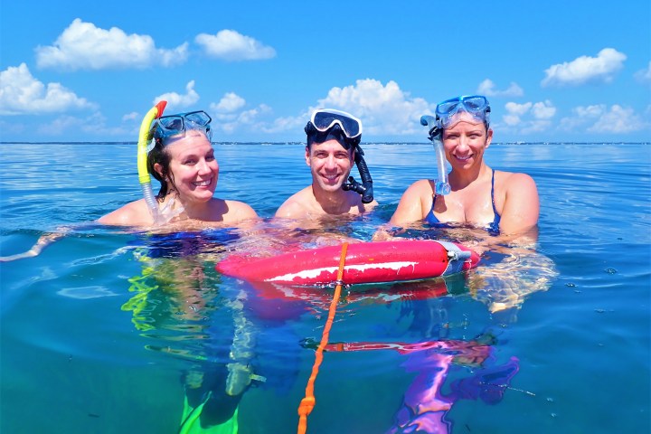 Three people with snorkel gear on treading water